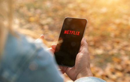 AACHEN, GERMANY - 31. August 2019 : Netflix app on Apple iPhone. Young man is browsing the movie...