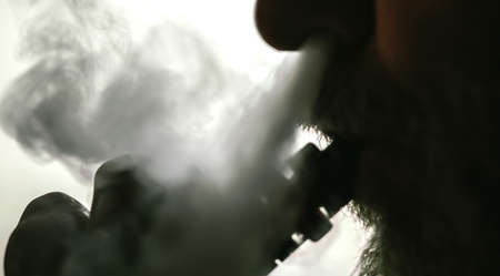 Man with concealed identity smoking a controversial vape is a health riskの写真素材