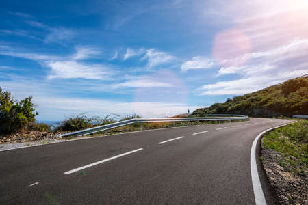 Empty long mountain road to the horizon on a sunny summer day at bright sunsetの写真素材