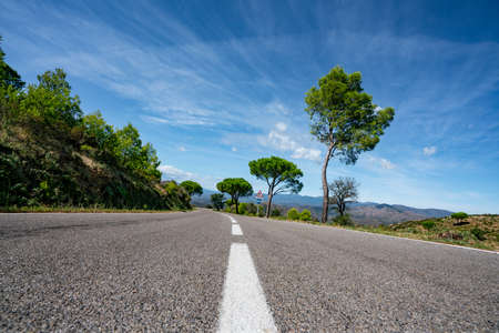 Empty long mountain road to the horizon on a sunny summer day at bright sunsetの写真素材