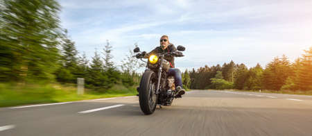 modern scrambler motorbike on the forest road riding. having fun driving the empty road on a motorcycle tour journey without helmet. copyspace for your individual text.の写真素材