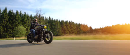 modern scrambler motorbike on the forest road riding. having fun driving the empty road on a motorcycle tour journey without helmet. copyspace for your individual text.の写真素材
