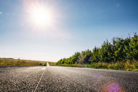 Empty long mountain road to the horizon on a sunny summer day at bright sunsetの写真素材