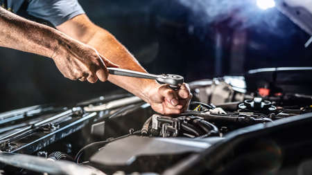 Auto mechanic working on car engine in mechanics garage. Repair service. authentic close-up shot - selective focus with motion blurの写真素材
