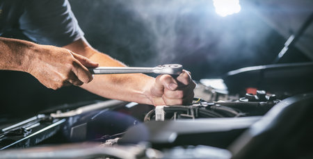 Auto mechanic working on car engine in mechanics garage. Repair service. authentic close-up shot - selective focus with motion blurの写真素材