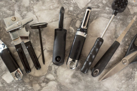 Black and steel kitchen gadgets shot overhead on a granite counter top.