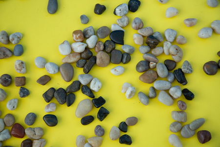 A pile of brown pebbles on yellow background with copy space.の写真素材