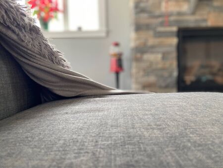 Gray couch with cozy blanket with blurred out background.の写真素材