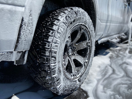 A truck with soapy suds all over it on a sunny day.