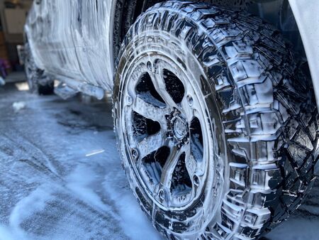 A truck tire with soapy suds all over it on a sunny day.の写真素材
