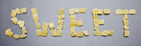 Word sweet from dried pineapples on the light grey background