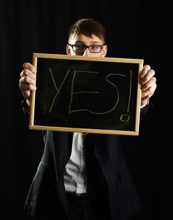 Young man holding blackboard with text YESの写真素材