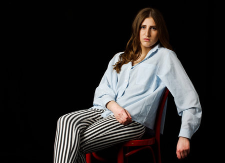 Young woman siting on the chair low keyの写真素材