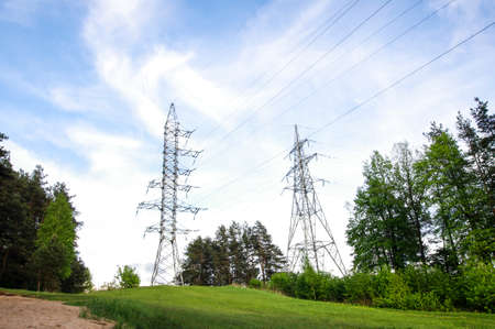 Electric line pylon on the green hill over blue skyの写真素材