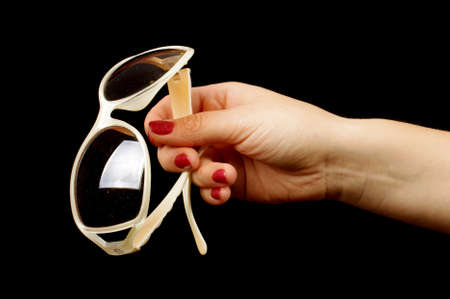 Female hand holding stylish sunglasses on the black backgroundの写真素材