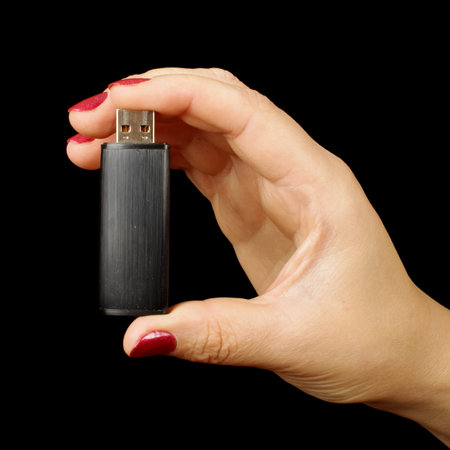 Female hand holding USB flash isolated on the black background