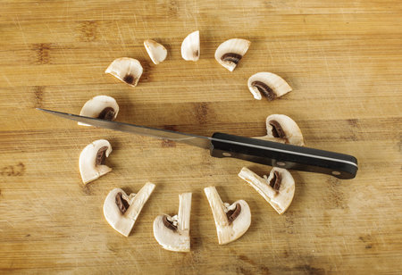Creative phototgraphy: slices of champignon mushroom and knife as a clockの写真素材