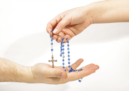 Female hand sharing rosary with male hand