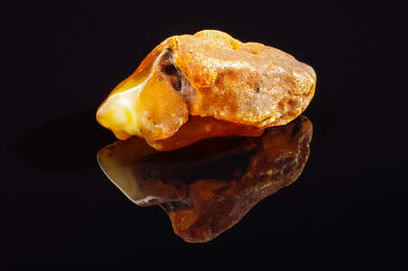 Huge piece of amber isolated on the black reflective surfaceの写真素材