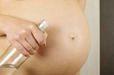 Pregnant belly and woman holding vodka bottleの写真素材