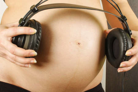 Pregnant mother playing lullaby with headphonesの写真素材