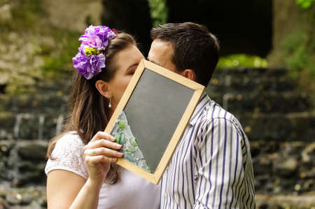 Young lovers kiss behind school black boardの写真素材