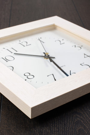 Office clock isolated on the dark wooden background