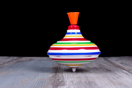 Plastic spinning top toy isolated on the reclaimed oak surface