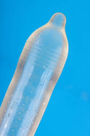 Ribbed and dotted condom full of water isolated on the blue backgroundの写真素材