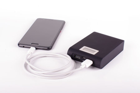 Smart phone connected with charging cable to power bank. Charging on the go