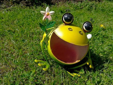 Funny thin metal frog as garden decoration on the green grassの写真素材