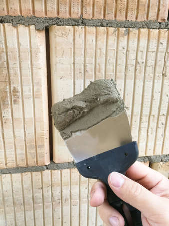 Construction worker hand holding taping knife tool with glues at construction siteの写真素材