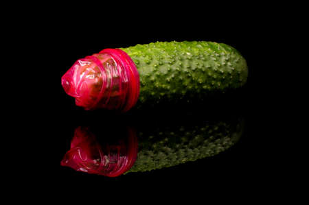 Pink condom on the big green cucumber. The concept of sexual educationの写真素材