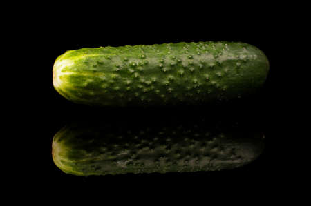 Tasty fresh organic green cucumber isolated on the black reflective surfaceの写真素材
