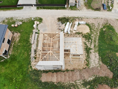 Aerial view of new house under construction at construction site. Roof construction in progress.