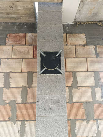 Porous concrete chimney under construction close to ceramic block wall inside the houseの写真素材