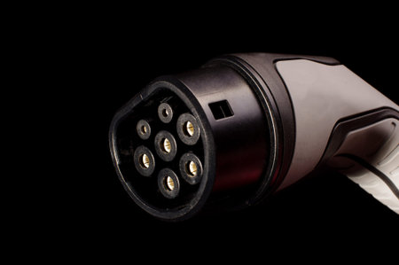 Charging plug for ecological electric cars in front of gray background ready for charging isolated...