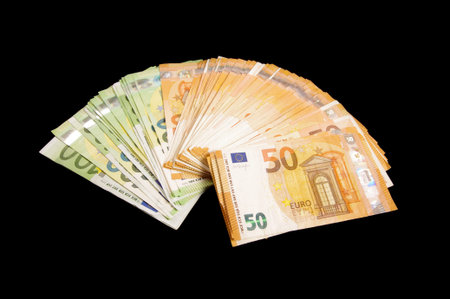 Pile of 50 and 100 euro banknotes isolated on the black background