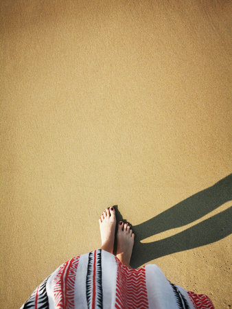 Barefoot girl standing on the sand in front of upcoming Baltic sea waves