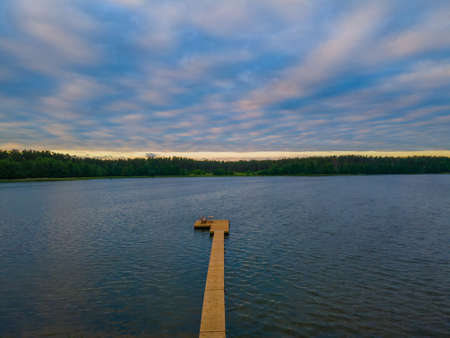 Footbridge to the lake with a blue cloudy sky in the eveningの写真素材