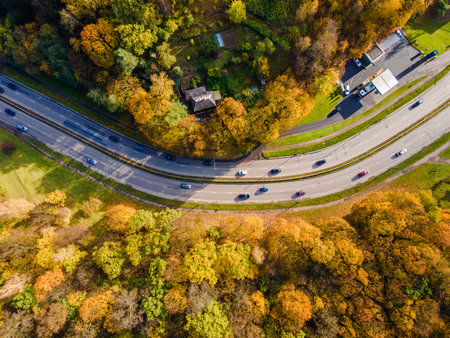 Aerial view of road bend with traffic in the autumn with falling golden trees around