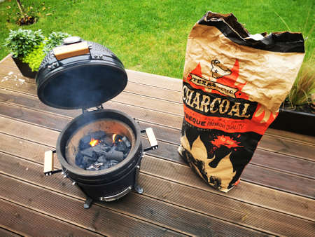 Kaunas / Lithuania - 10 19 2020: A kamado type barbeque grill with a bag of charcoal standing on a living house terraceのeditorial素材