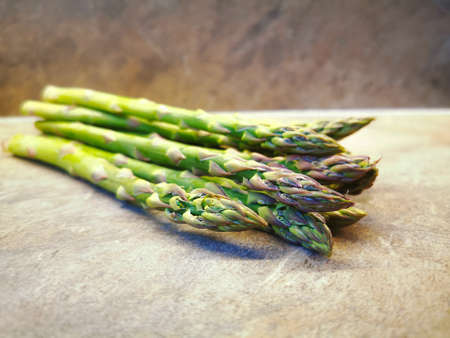 Freshly cut green fresh raw asparagus on a marble tableの写真素材