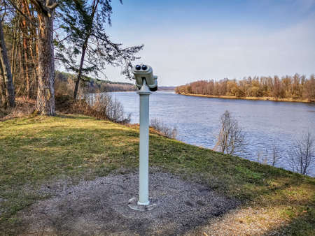 Binoculars in the park on the meadow to observe the panorama of the bend of the riverの写真素材