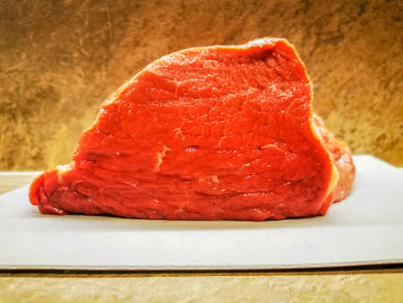 Freshly cut piece of raw red beef ham on a cutting boardの写真素材