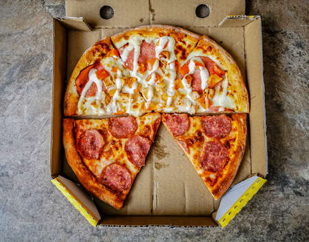 Pieces of two different fresh pizza slices in a cardboard pizza boxの写真素材