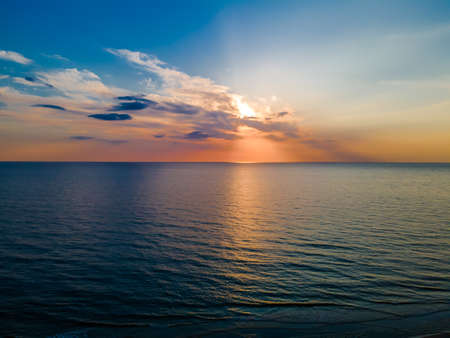 Beautiful sunset and colorful cloudscape over a slightly undulating seaの写真素材
