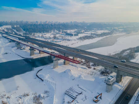Aerial view of the bridge under construction over the river in winter with huge traffic. New bridge is being built next to the old oneの写真素材