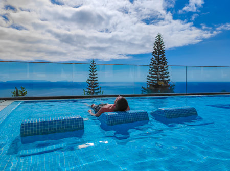 Young girl lying and sunbathing on a sunbed in a water in a panoramic poolの写真素材
