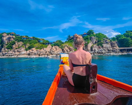 First person view of a traditional long tail boat with a girl sitting in front in Andaman sea in Thailand, Koh Tao islandの写真素材